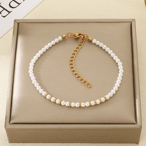 Gros plan d'un bracelet de perles blanches avec perles dorées et fermoir en métal doré