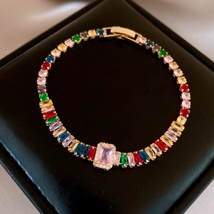 Detail of tennis bracelet with colorful rectangular gemstones and gold-plated clasp
