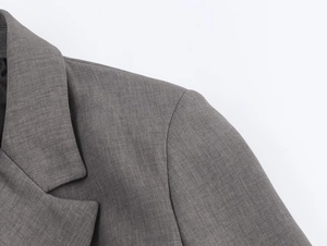 Détail du revers et de l'épaule d'un blazer gris avec une texture de tissu fine et précise