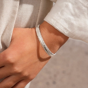 Detailed close-up of silver bangle with textured woven finish on minimalist model