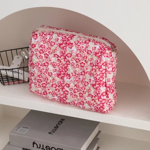 Detailed close-up of quilted floral cosmetic bag with red flowers and zip closure