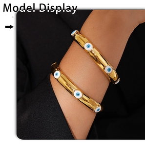 Detailed view of 18k gold plated evil eye bracelets worn on model wrist with a dark background