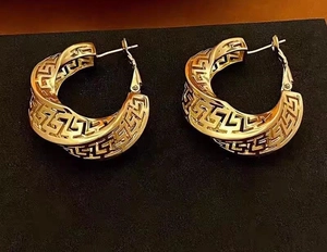 Macro shot of gold hollow geometric Greek key pattern on vintage C-shaped hoop earrings