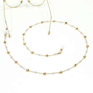 Detail view of golden eyewear chain with elegant heart beads and small white pearls
