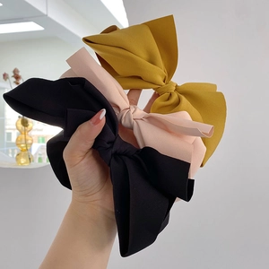 Detailed view of three cloth bow headbands in pink, yellow and black colors
