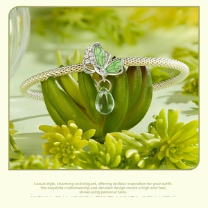 Macro detail of S925 silver butterfly charm with green enamel and teardrop stone