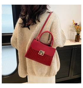 Detail of red crocodile texture leather bag with gold buckle and stylish top handle