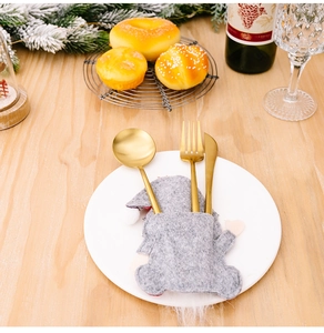 Close-up of golden cutlery set in a grey gnome felt holder on a festive Christmas table