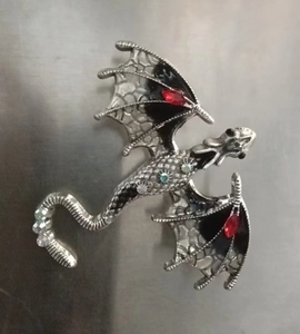 Detailed view of vintage silver dragon brooch with red gemstones and colorful enamel inlay