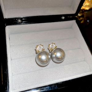 Gros plan de boucles d'oreilles perles gris argent avec zircon et serti griffes doré