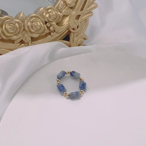 Macro detail of elastic beaded ring with blue marble stones and gold spherical spacers