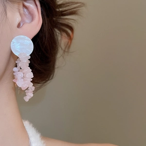 Close-up of shell and pink quartz bow tassel earrings worn on ear with elegant drape