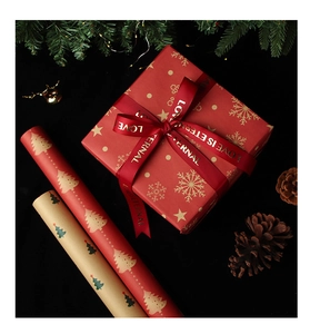 Close-up of Christmas kraft wrapping paper with festive tree patterns and red ribbon