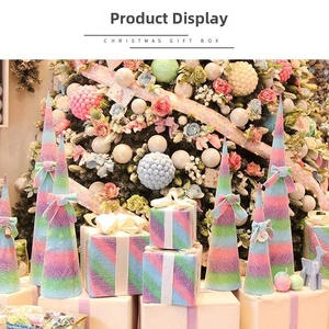 Dettaglio di alberi di Natale sfumati macaron e scatole regalo con fiocchi di seta in scena