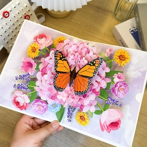 Detail showing 3D pop-up butterfly and hydrangea card held against a warm desk background