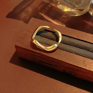Detail showing the 18k gold plated irregular wave ring on a luxury wooden display stand