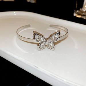 Detailed view of silver butterfly open bangle with sparkling crystals on ceramic tray