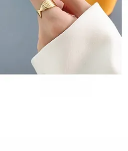 Detalle de anillo bañado en oro de 18K con textura de concha en la mano de una modelo