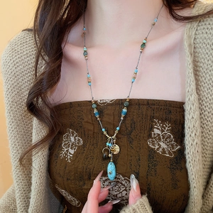 Dettaglio di una collana boho con perline turchesi e un ciondolo a forma di goccia