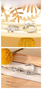 Detail view of silver heart-shaped ear cuffs with arrow design on a wooden jewelry box