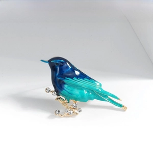 Detail of bird brooch featuring gradient enamel, white rhinestones and gold-plated alloy