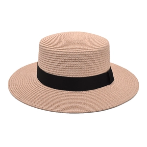 Detail of pink straw boater hat featuring fine weave texture and black grosgrain ribbon