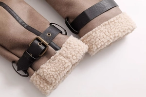 Detailed view of dark brown suede jacket cuff with white shearling lining and metal buckle