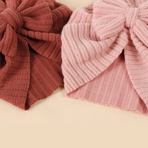 Detailansicht von gerippten Baby-Turban-Hüten mit großen Schleifen in Ziegelrot und Rosa