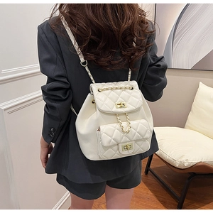 Detail of white quilted leather backpack with gold chain straps on female model