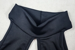 Close-up of black hollow-out high neck jumpsuit showing knit fabric and cutout detail
