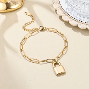 Macro detail of 18K gold paperclip chain bracelet with a polished padlock pendant charm