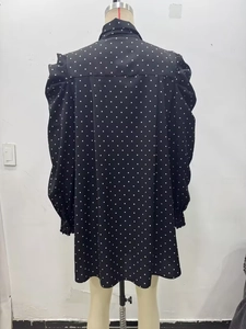 Vista posteriore dettagliata di un abito nero a pois con maniche a sbuffo su manichino