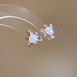 Detailed macro view of bow-knot pearl stud earrings with shimmering gold finish