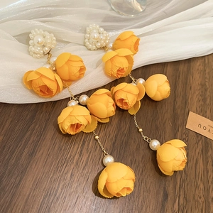 Close-up of elegant yellow rose fabric flower earrings with long pearl tassel drops.