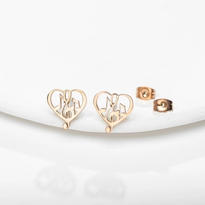 Elegant rose gold heart earrings with music note design on minimalist white platform
