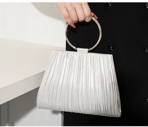 Detail of silver pleated evening bag featuring a round metal ring handle for elegant grip