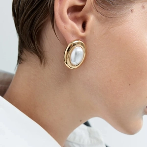 Vintage gold-tone oval stud earrings with white pearl inlay shown on model's ear