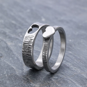 Detailed close-up of couples stainless steel rings with complementary heart shapes