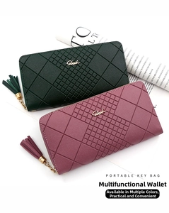 Detail of long quilted wallet with tassel zipper and metal logo in dark green and purple