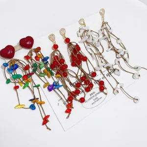 Handmade heart acrylic shell tassel earrings set with colorful beads on white background