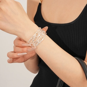 Détail d'un bracelet ajouré argenté large avec des lignes entrelacées de style artistique