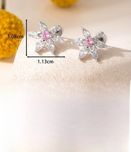 Macro shot of silver flower earrings with pink heart zircon and leaf-shaped details