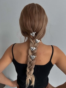 Détail de quatre pinces à cheveux coeur en métal argenté sur une coiffure tressée de mannequin