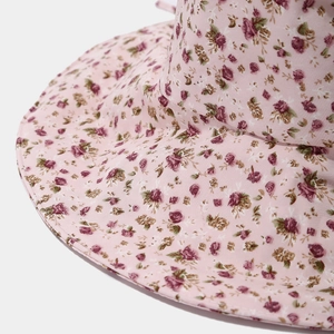 Gros plan du motif floral rose et des coutures fines sur le large bord du chapeau