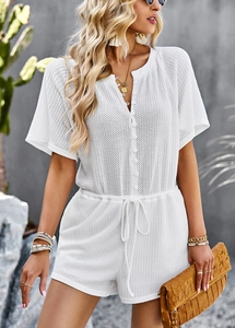 Detail of white textured romper with V-neck, buttons, and drawstring waist for casual wear
