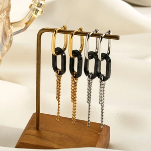 Macro shot of long resin drop earrings with geometric rings on a stylish display stand
