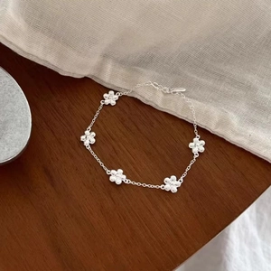 Elegant s925 silver flower bracelet with five small floral charms on a wooden background