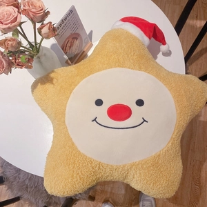 Nahaufnahme eines gelben Plüschstern-Kissens mit Weihnachtsmütze und lächelndem Gesicht
