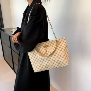Borsa tote beige con motivo marrone e tracolla a catena dorata indossata dal modello