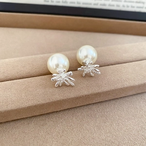 Macro shot of silver fireworks earring with pearl and cubic zirconia on beige velvet tray